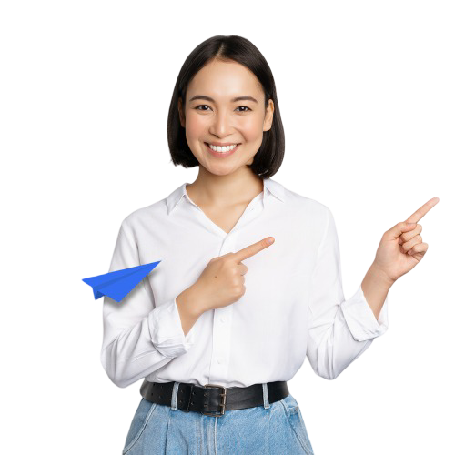 Uśmiechnięta młoda kobieta w białej koszuli wskazująca w bok, z niebieskim papierowym samolotem na tle, symbolizująca inspirację i nowoczesne podejście do nauki.